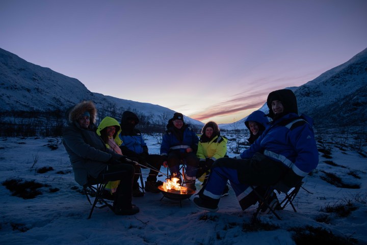 a group of people sitting on top of a snow covered mountain